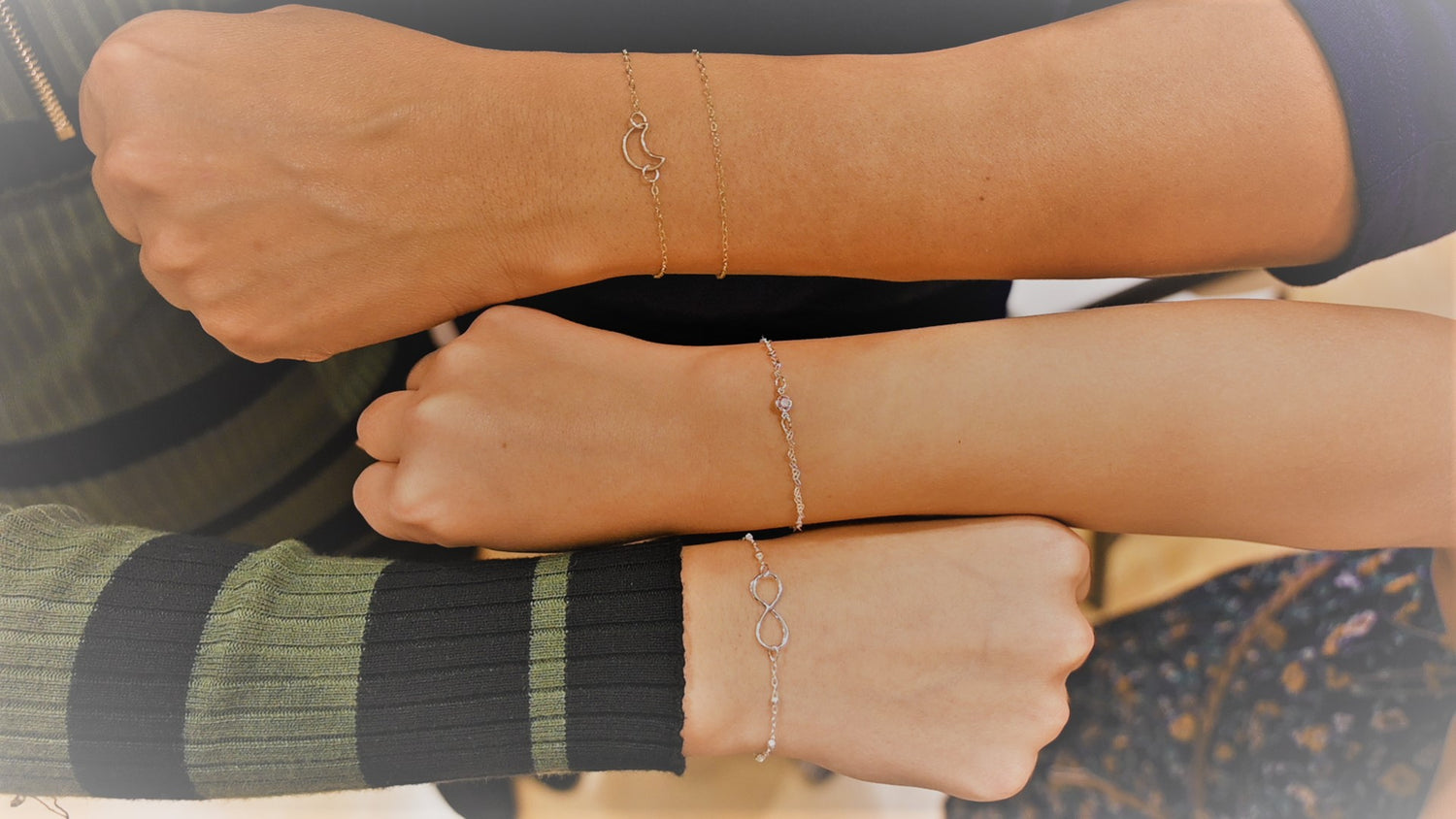 Permanent jewelry bracelets in sterling silver and gold-filled chains worn on layered wrists, featuring minimalist charm designs