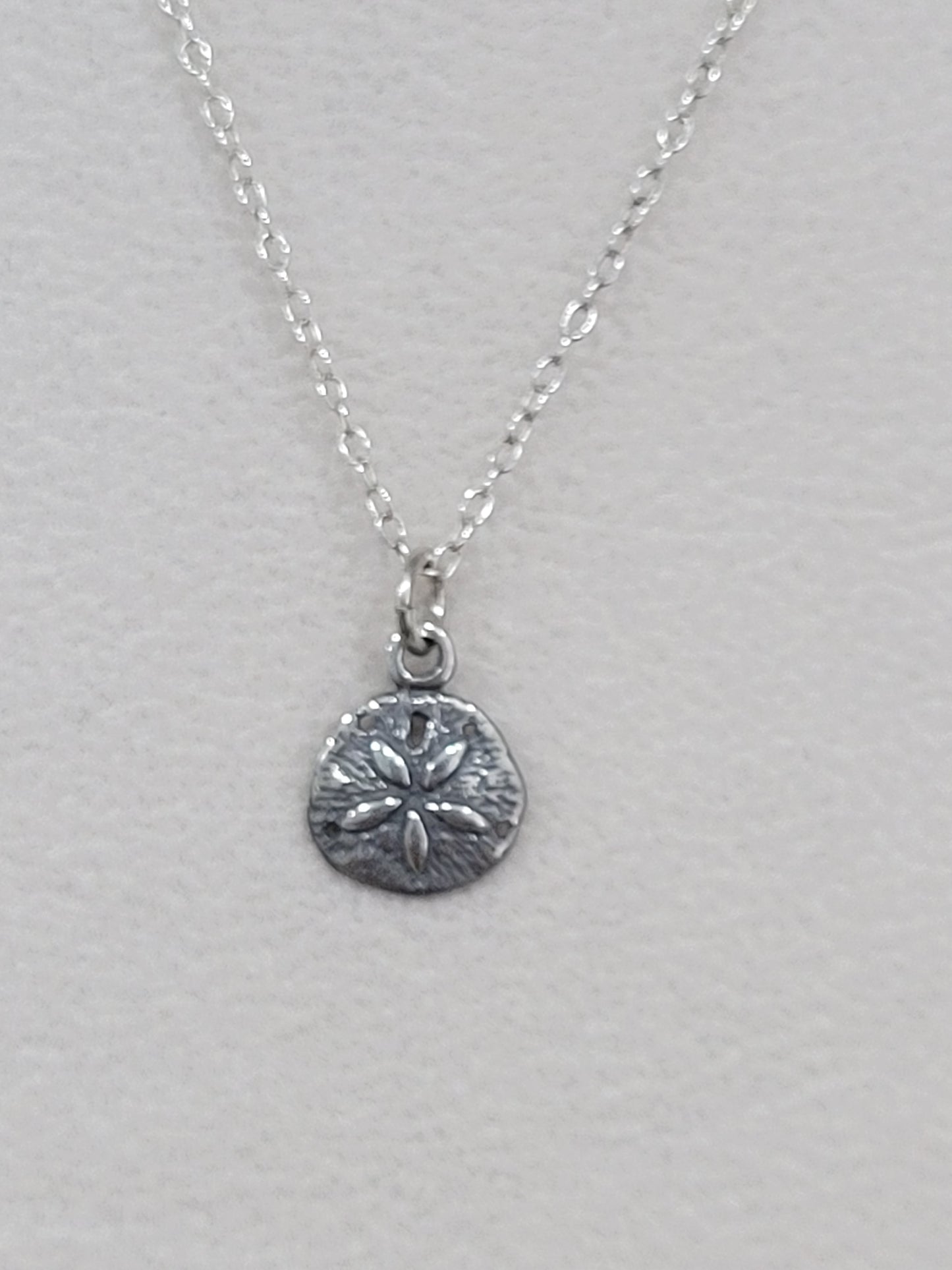 Sterling silver sand dollar necklace shown from an alternate angle on a silver chain