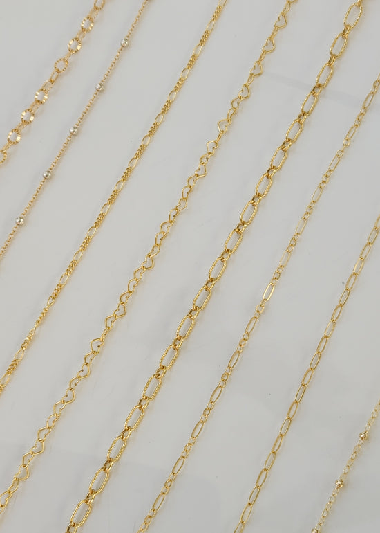 Close-up of 14k gold-filled permanent jewelry chains showing multiple delicate chain styles that do not tarnish