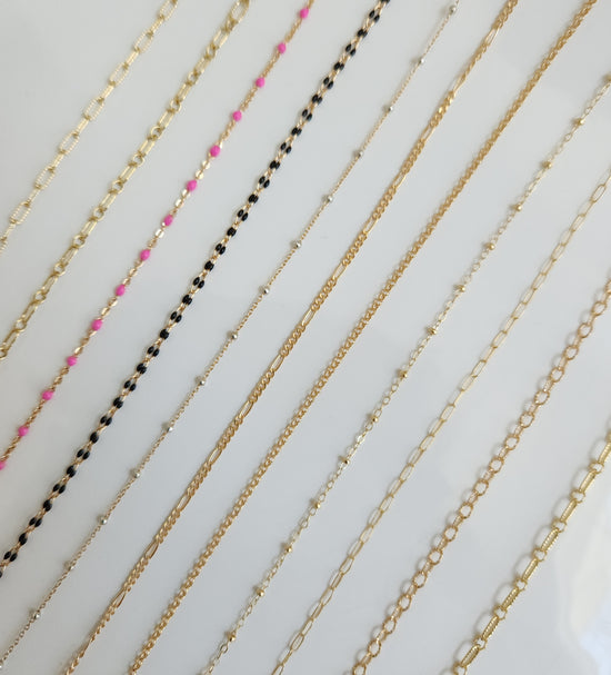 Selection of 14k gold-filled permanent jewelry chains showcasing multiple chain styles and textures