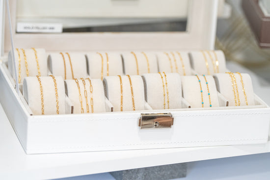 14k gold-filled permanent jewelry chains displayed in a showcase, offering a variety of delicate chain styles