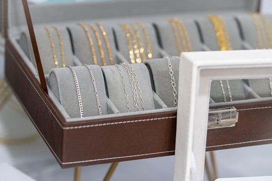 Display of 14k solid yellow and white gold chains for permanent jewelry in a studio showcase