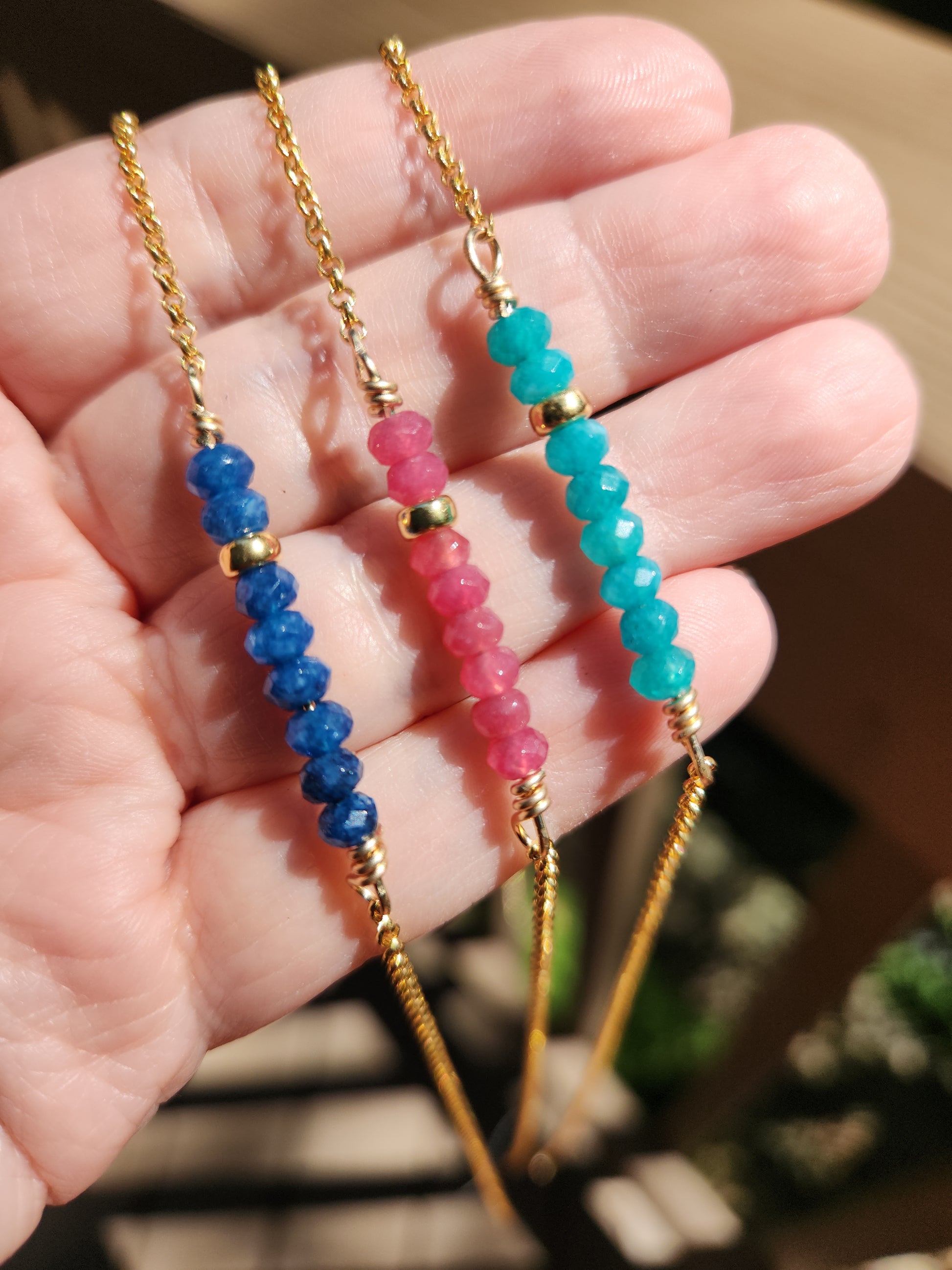Handcrafted beaded gemstone necklace with gold-filled chain shown worn in hand