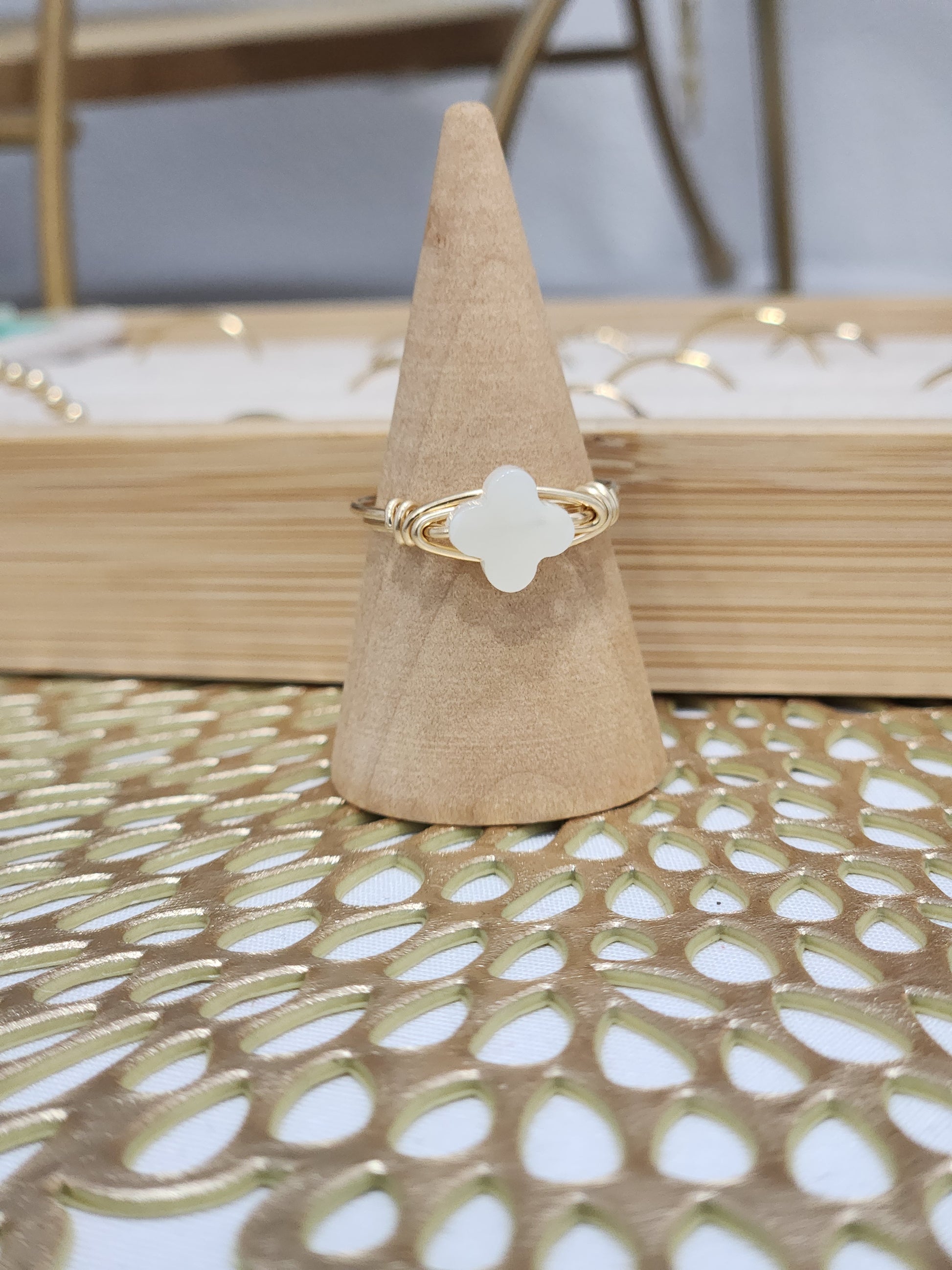 Mother-of-pearl clover wire-wrapped ring handcrafted with 14k gold-filled wire displayed on a ring stand