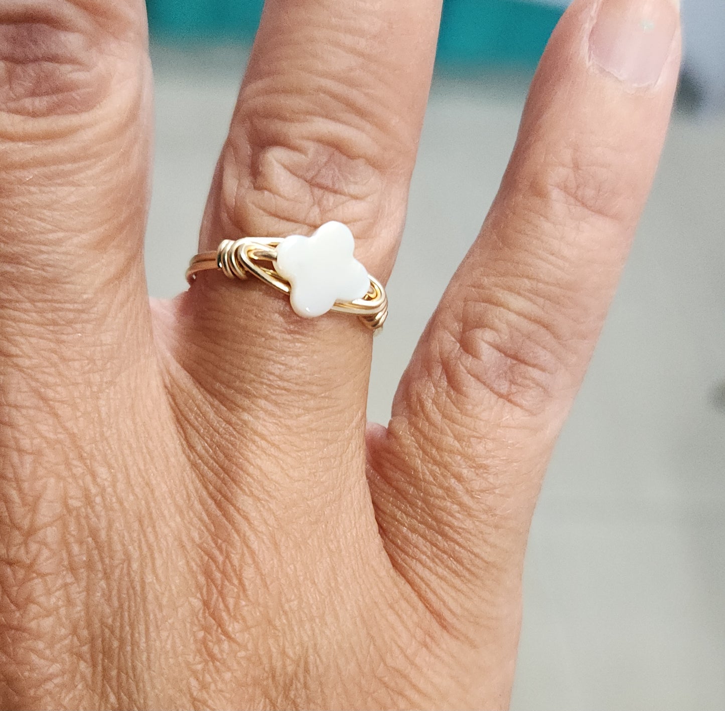 Mother-of-pearl clover ring made with 14k gold-filled wire worn on the hand
