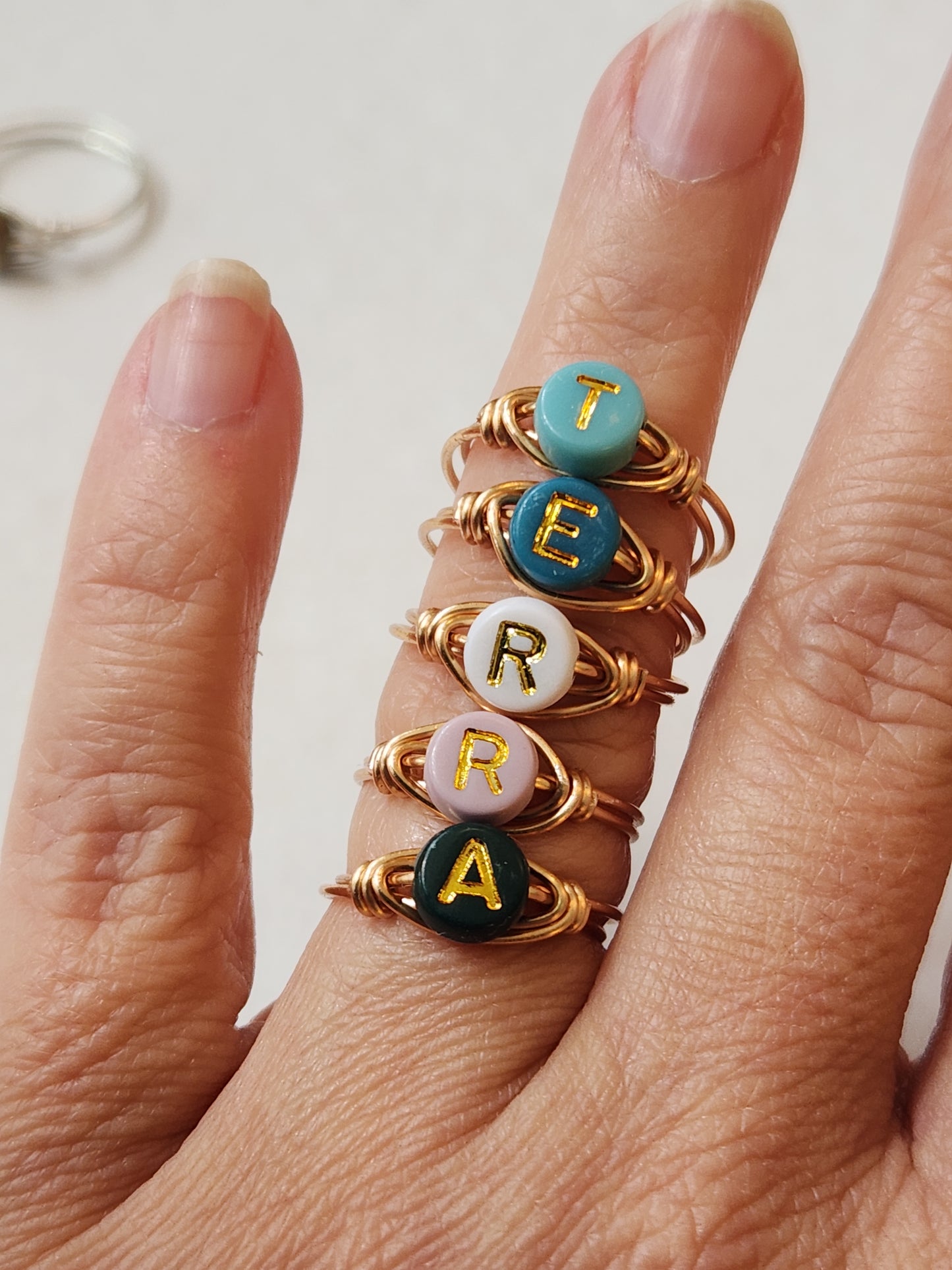Handmade initial ring with gold-filled wire shown worn on finger from an angled view
