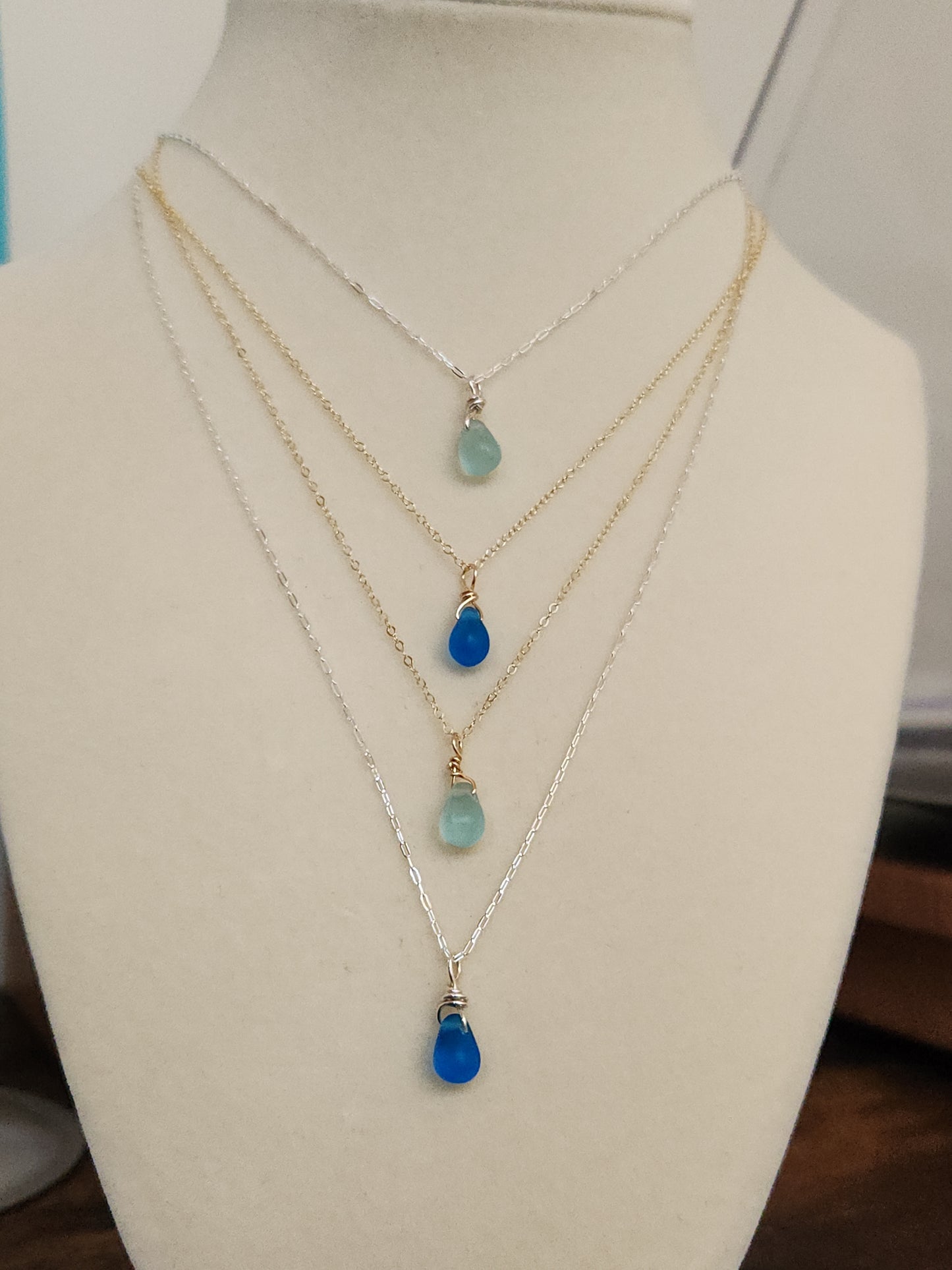 Two handcrafted sea glass necklaces layered, featuring light and dark blue glass pendants