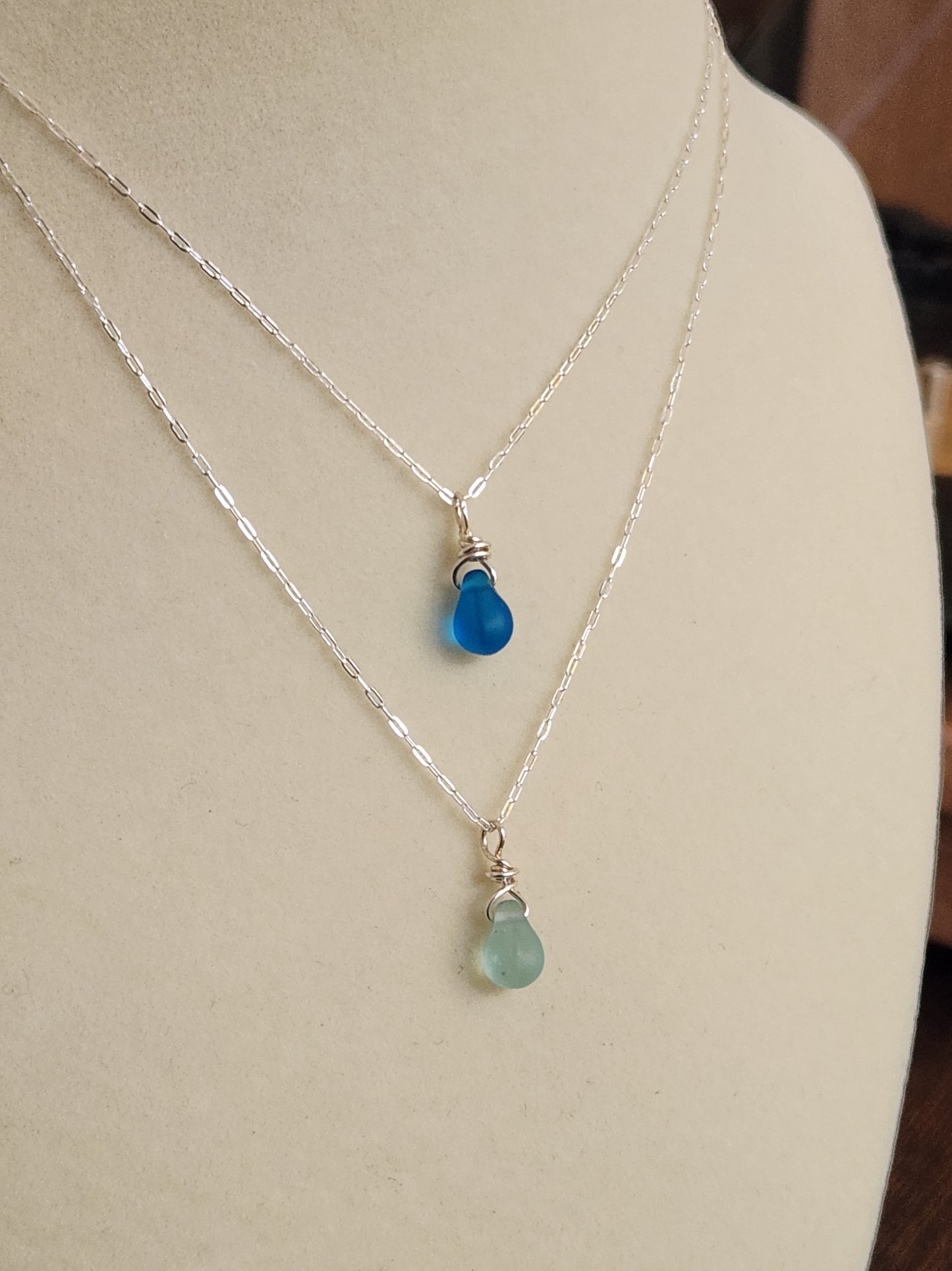 Light blue sea glass necklace worn on a mannequin bust with sterling silver chain