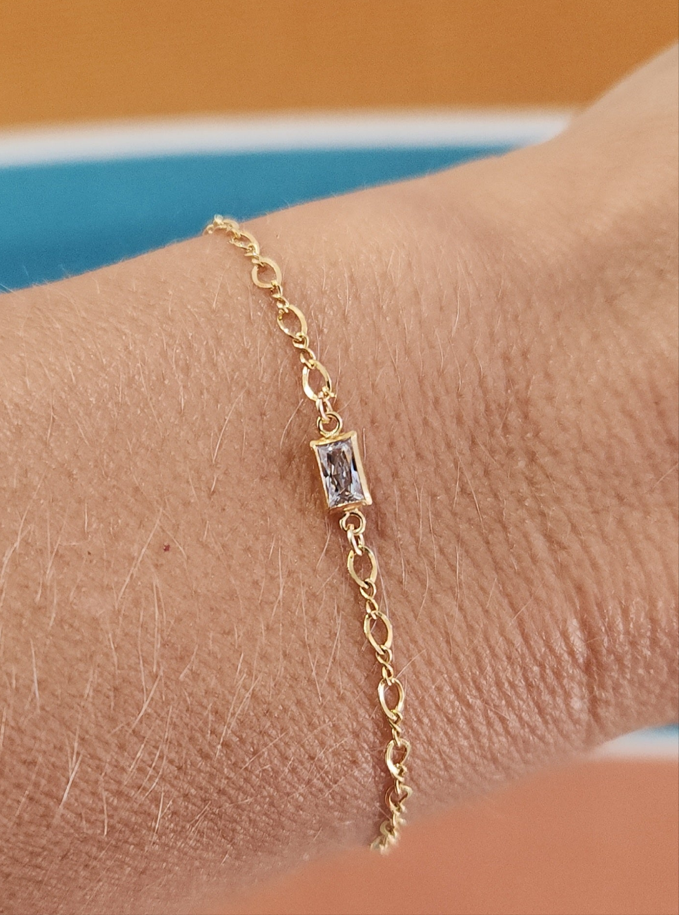Detail view of gold-filled infinity chain bracelet with diamond baguette accent
