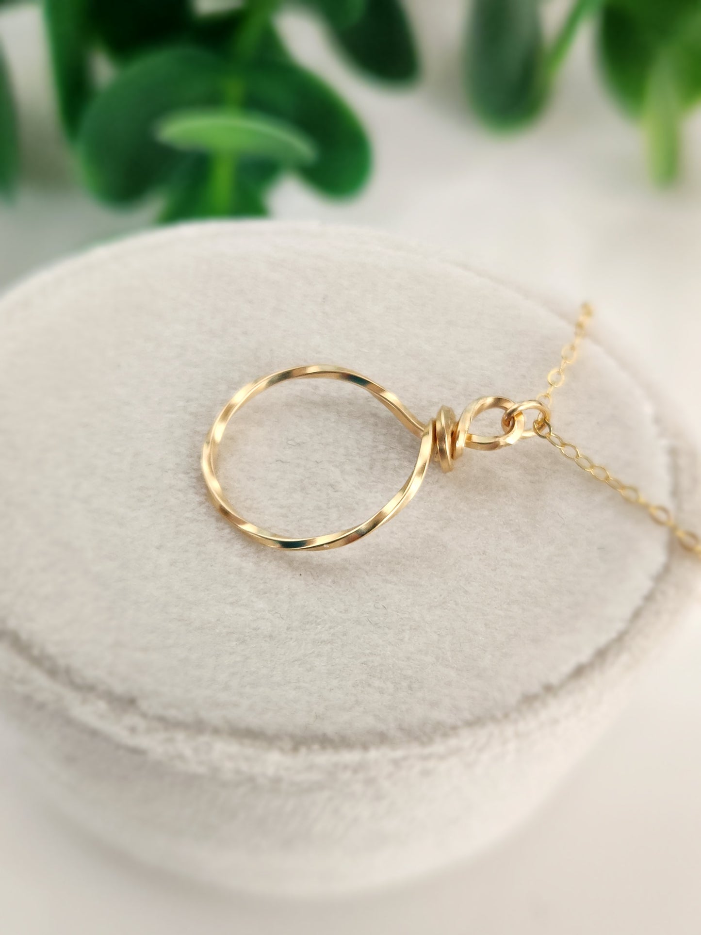 14k gold-filled hammered circle pendant necklace displayed on a neutral jewelry stand