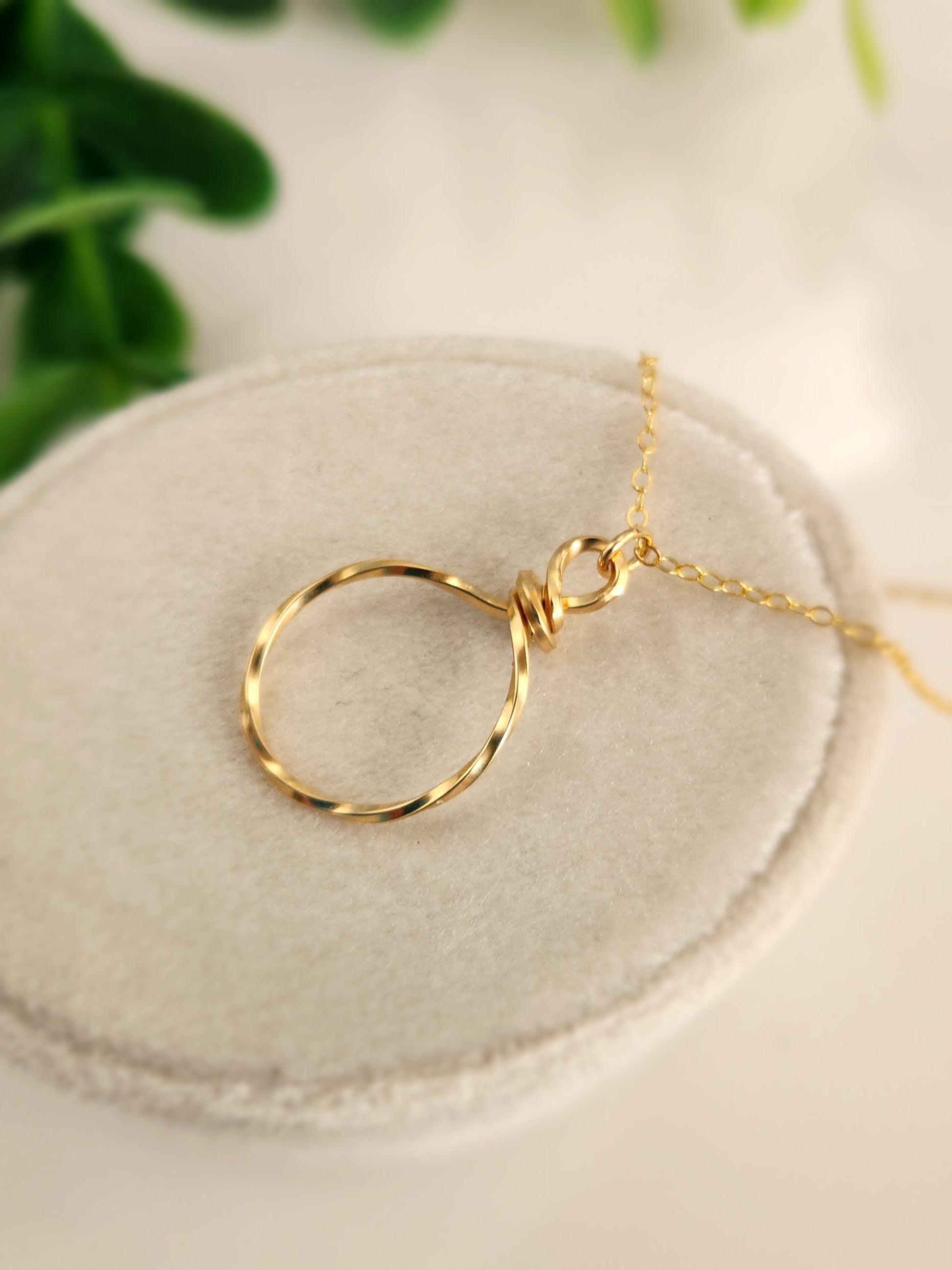 Close-up of a handcrafted hammered gold-filled pendant with textured wire finish