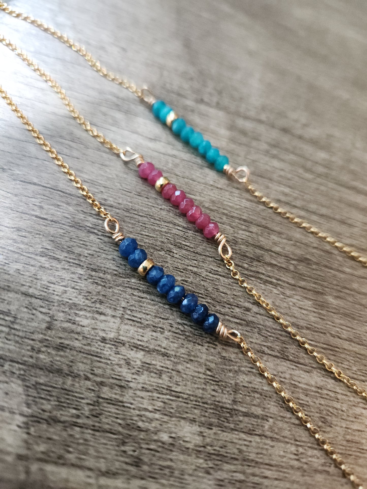 Layered 14k gold-filled beaded gemstone necklaces with faceted sapphire, ruby, and blue apatite