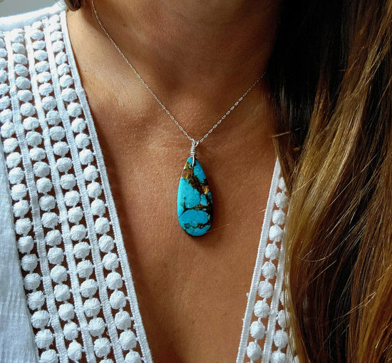 Handcrafted metalsmith artisan jewelry featuring a turquoise pendant necklace worn by a model, made in Destin, Florida