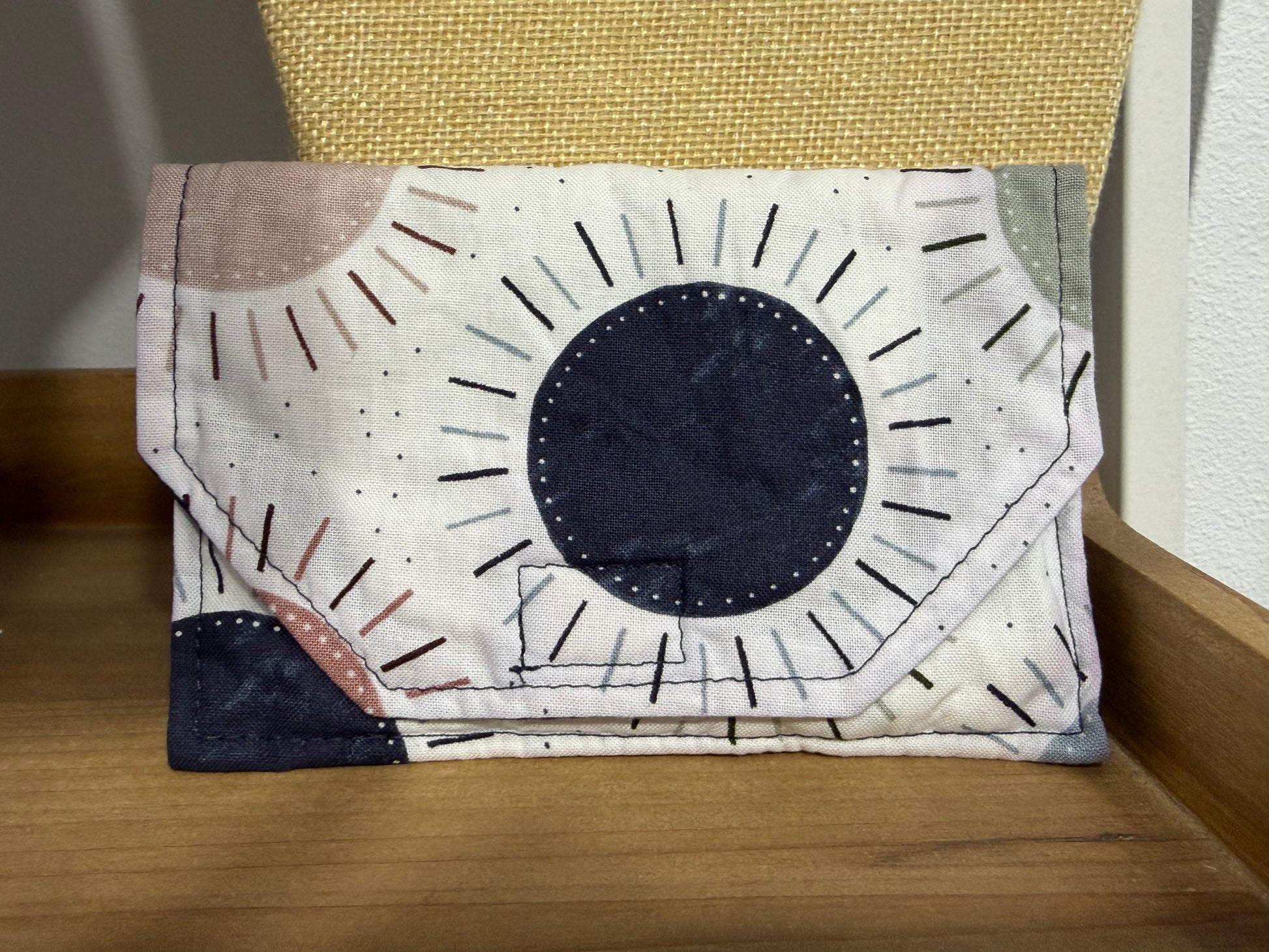 Close-up view of handmade fabric wallet with sunburst pattern and envelope-style closure