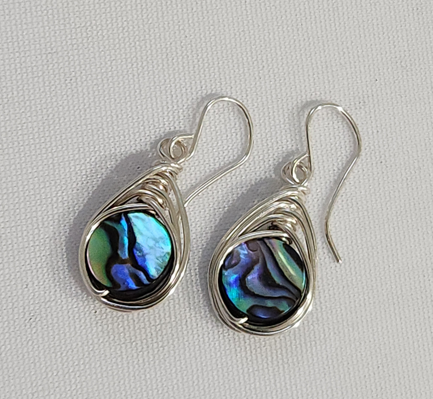 Ocean Glow abalone wire-wrapped earrings handcrafted with sterling silver wire, featuring iridescent shell centers
