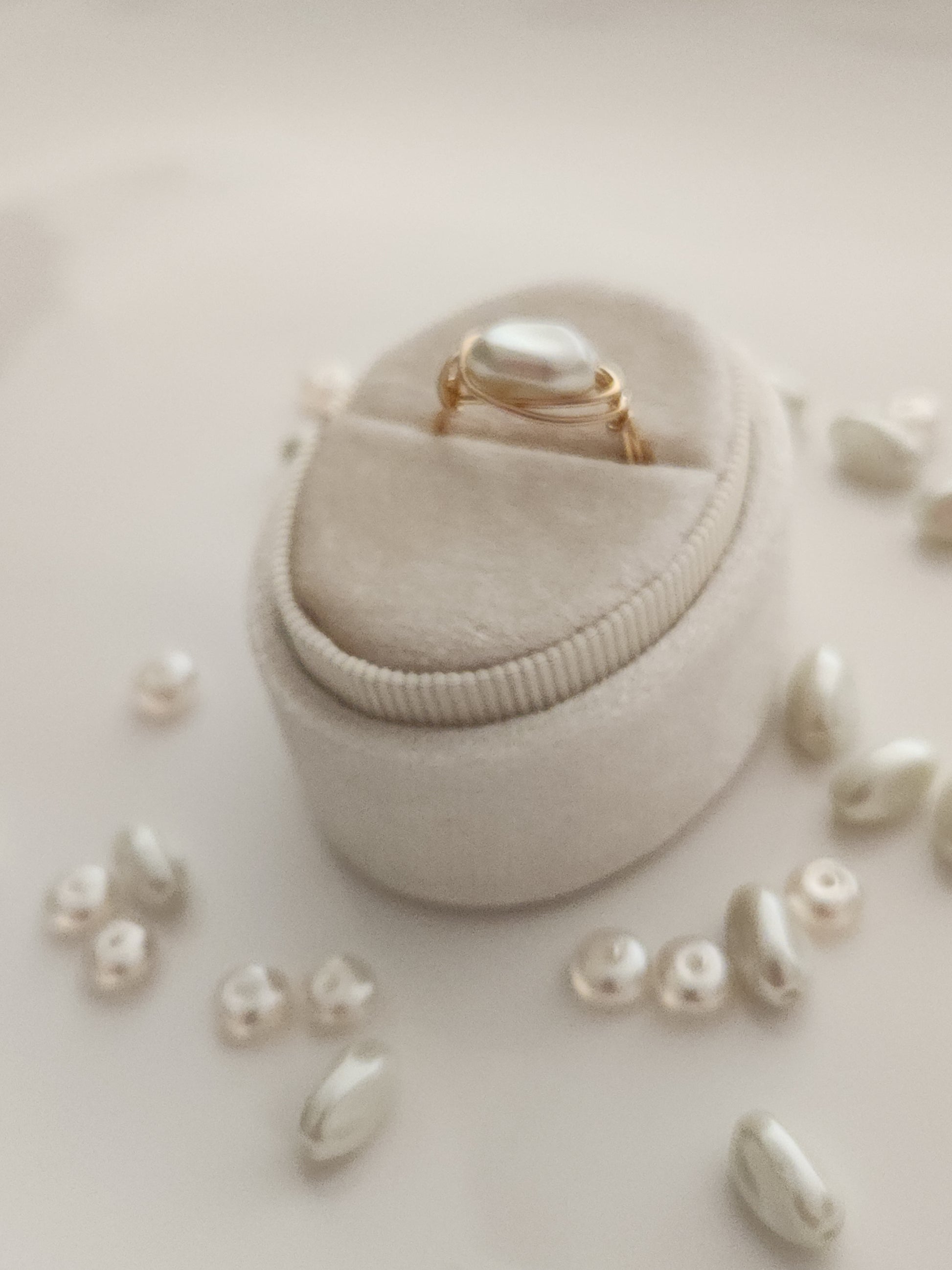 Handcrafted oblong pearl ring in 14k gold-filled wire styled in a flat lay with freshwater pearls
