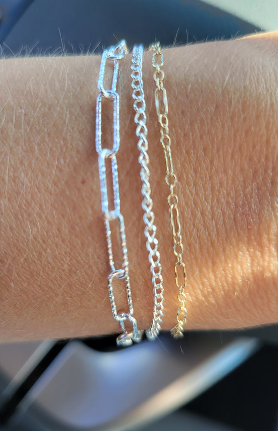 Permanent jewelry bracelets in sterling silver and 14k gold-filled worn on the wrist at Terra Handcrafted in Destin, Florida