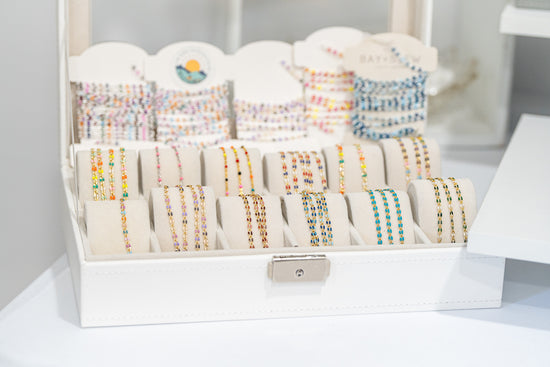 Display of colorful permanent jewelry chains and bracelets available for customization at a Destin, Florida studio