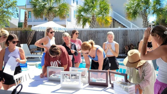 Group of guests gathered at an outdoor permanent jewelry pop-up event in Destin and Navarre, Florida, selecting chains and charms for custom permanent jewelry