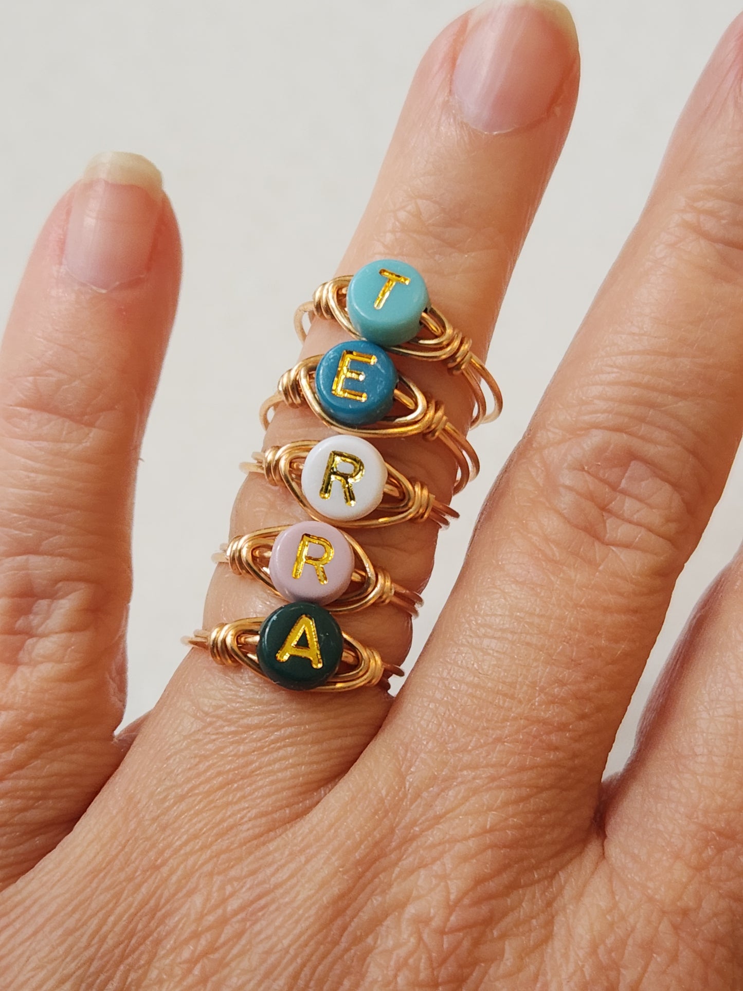 Personalized gold-filled initial ring worn on hand showing enamel letter detail
