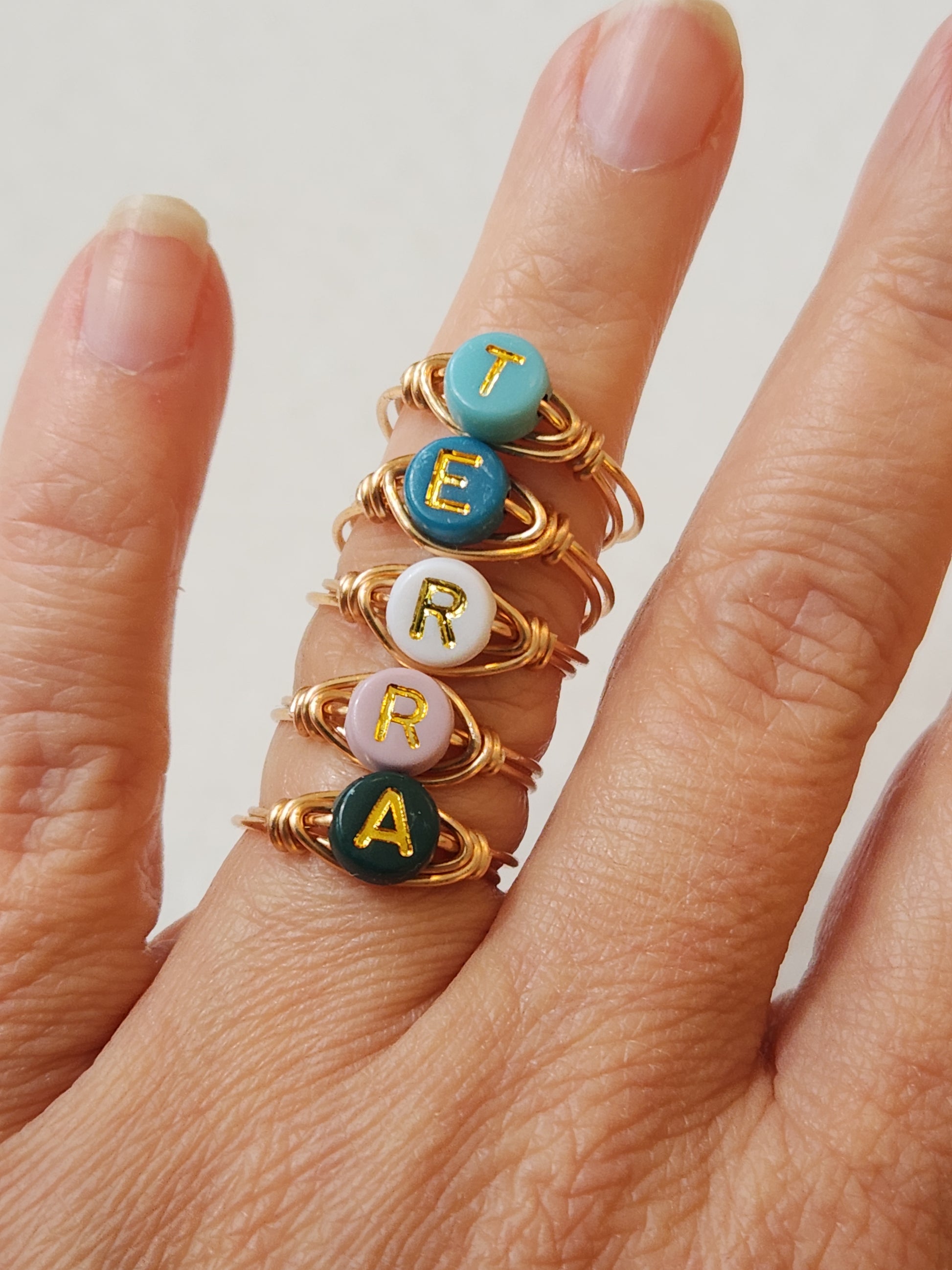 Personalized gold-filled initial ring worn on hand showing enamel letter detail