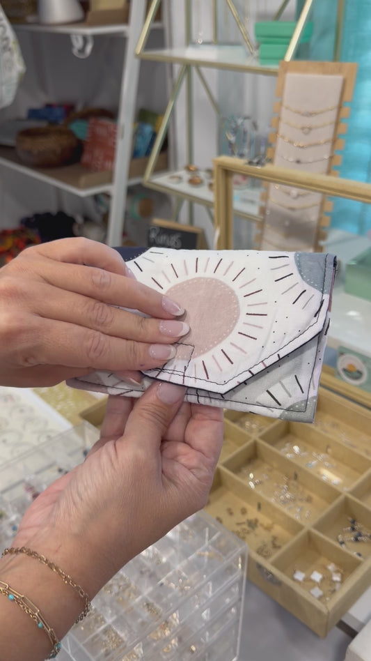 Video showing a handmade fabric wallet with a modern sunburst design being held and opened