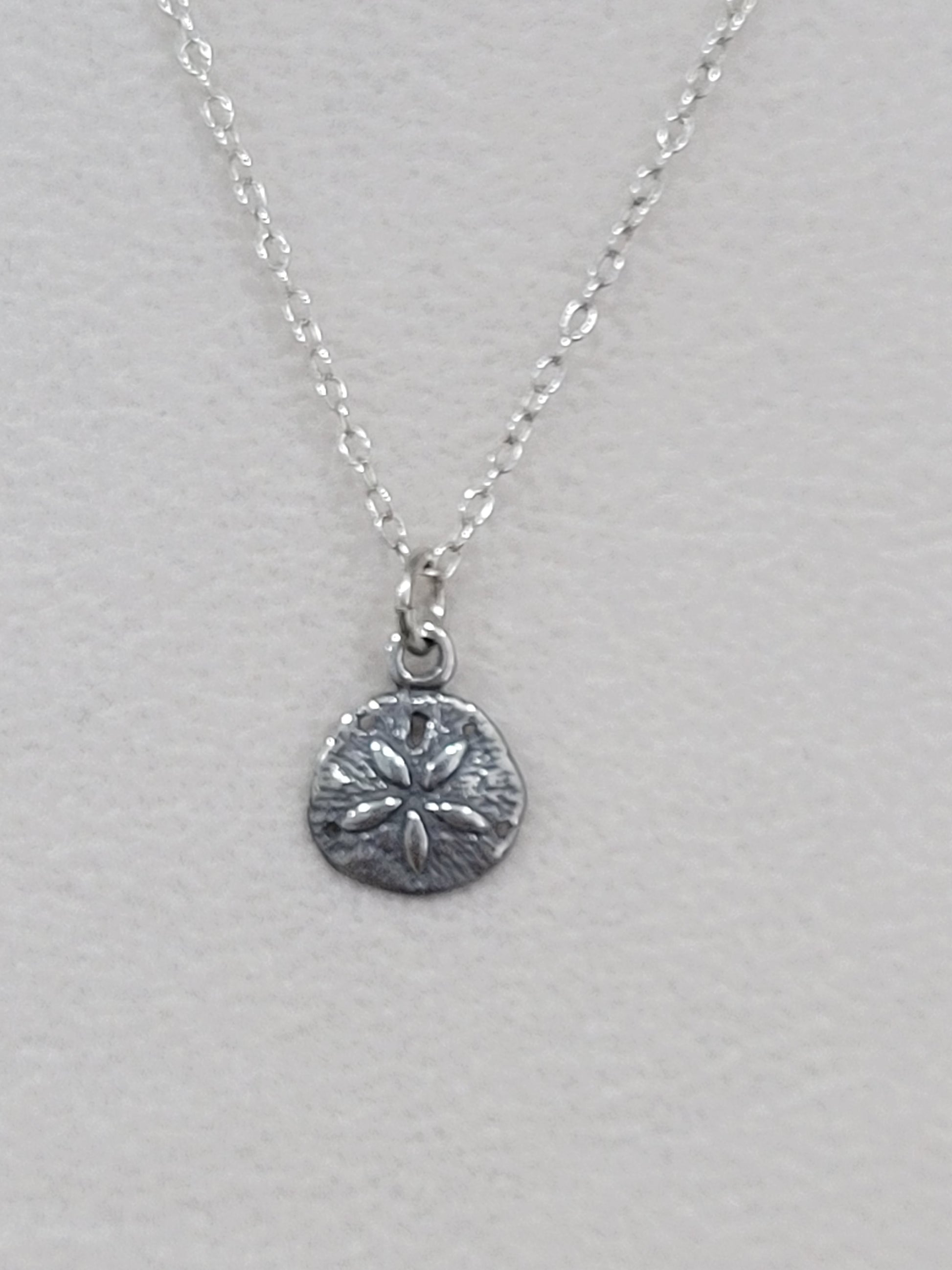 Sterling silver sand dollar necklace shown from an alternate angle on a silver chain