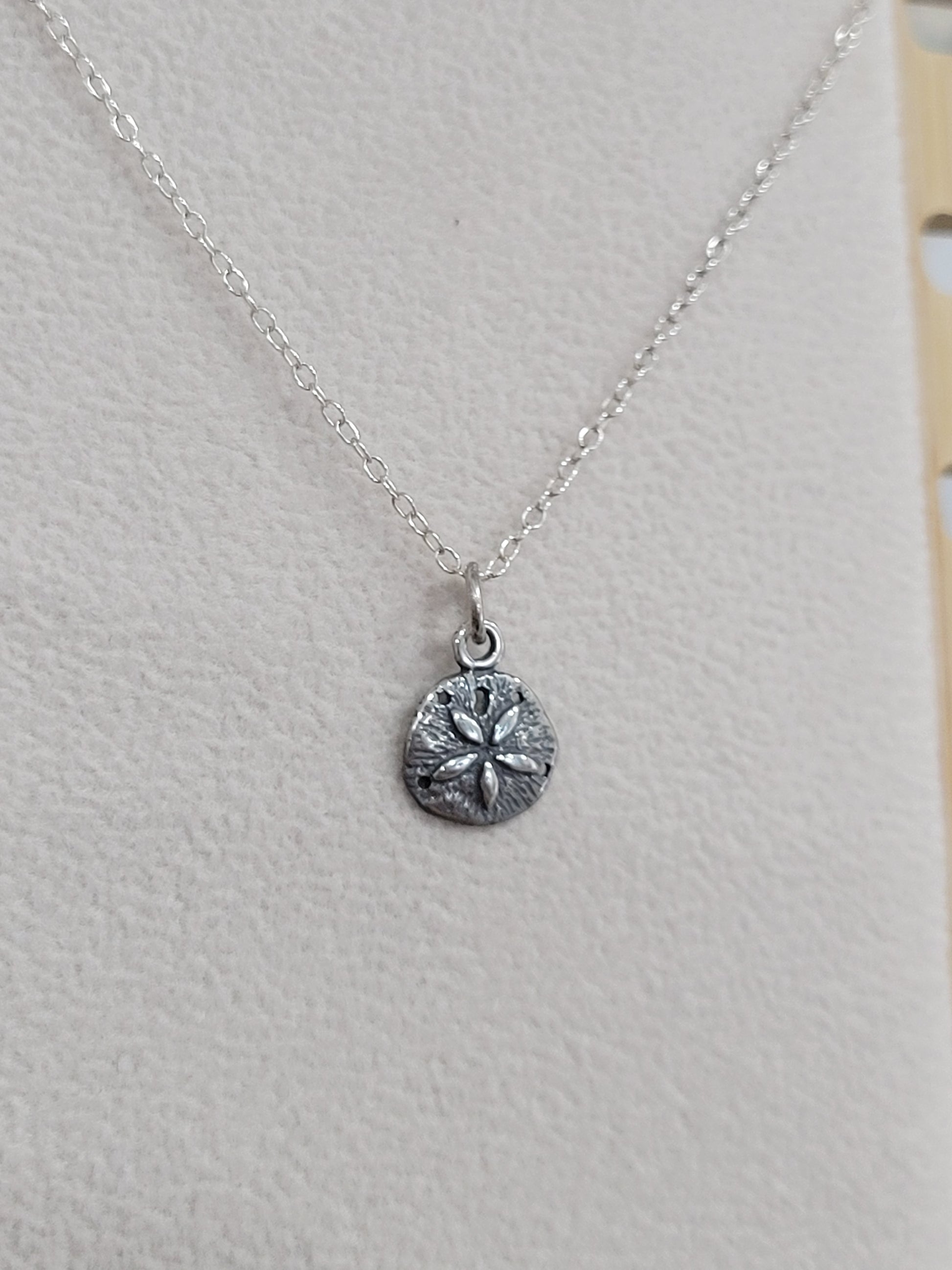 Sterling silver sand dollar pendant necklace worn on a mannequin, beach-inspired jewelry