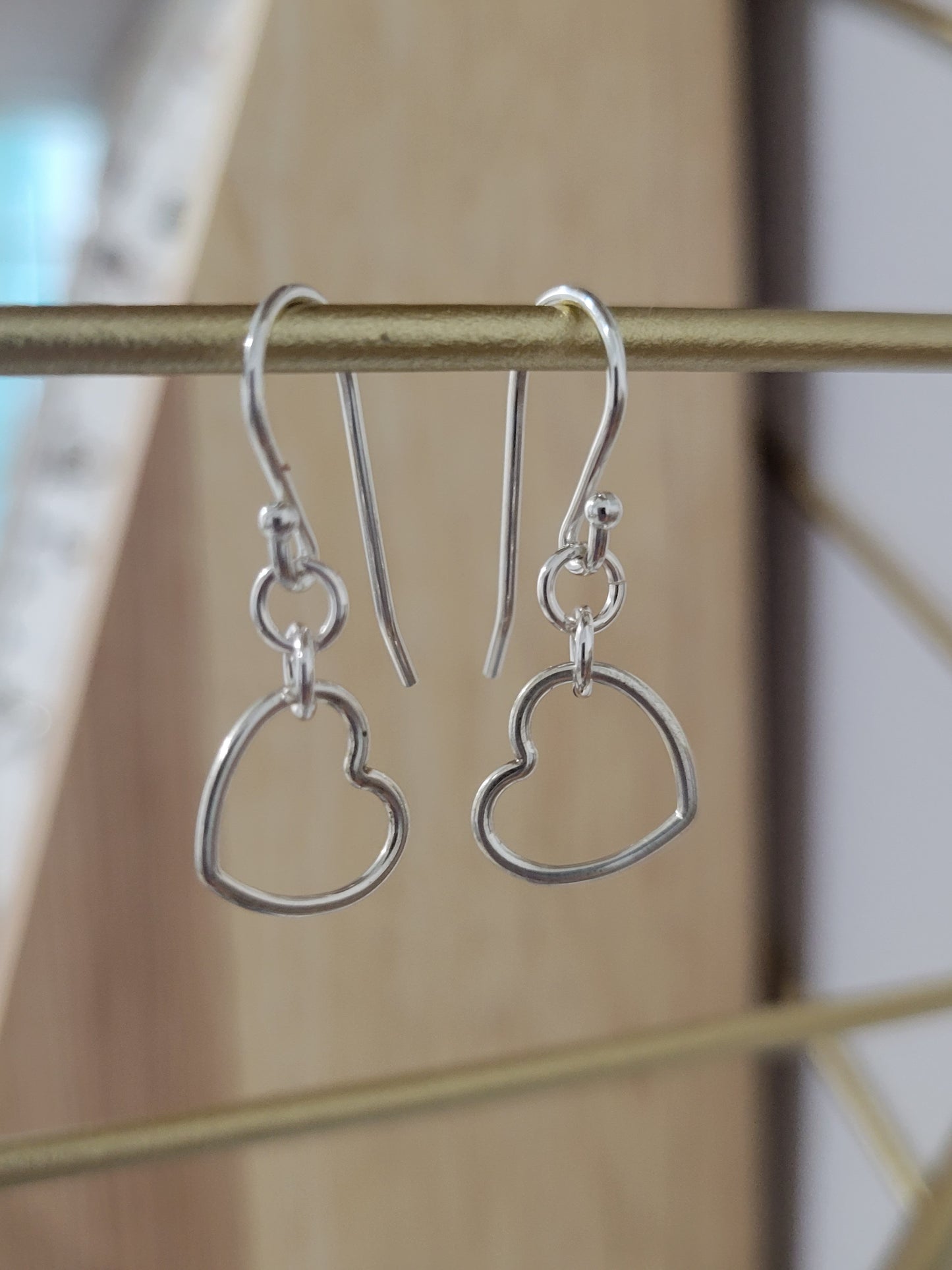 Sterling silver dainty heart earrings with open heart design hanging from silver ear wires