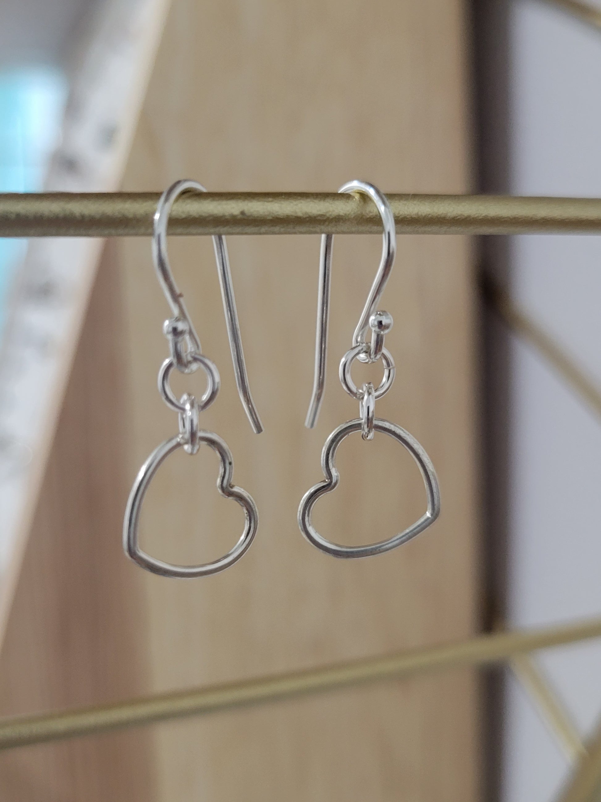 Sterling silver dainty heart earrings with open heart design hanging from silver ear wires