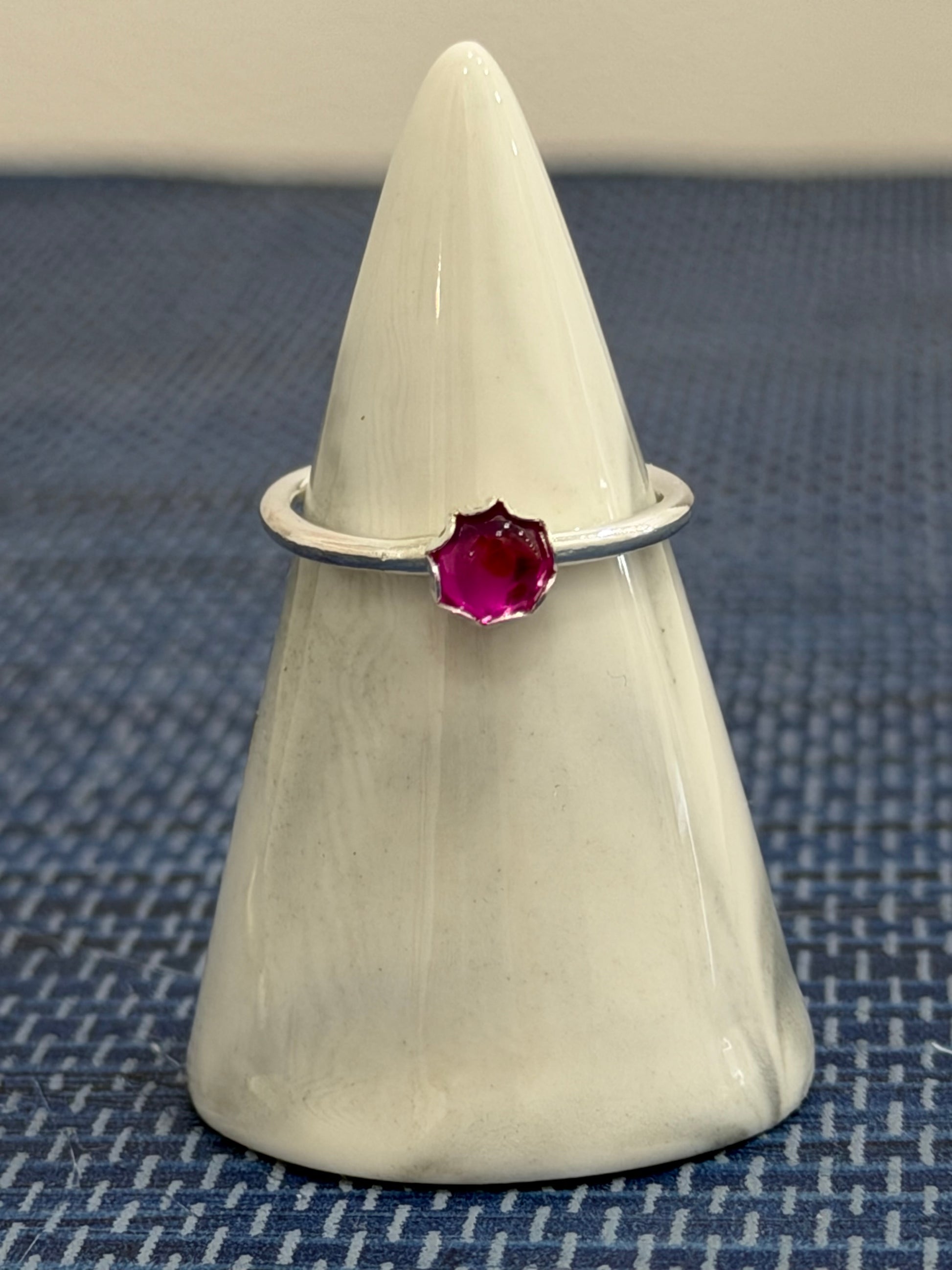 Sterling silver ruby ring with vibrant red gemstone displayed on a ring stand
