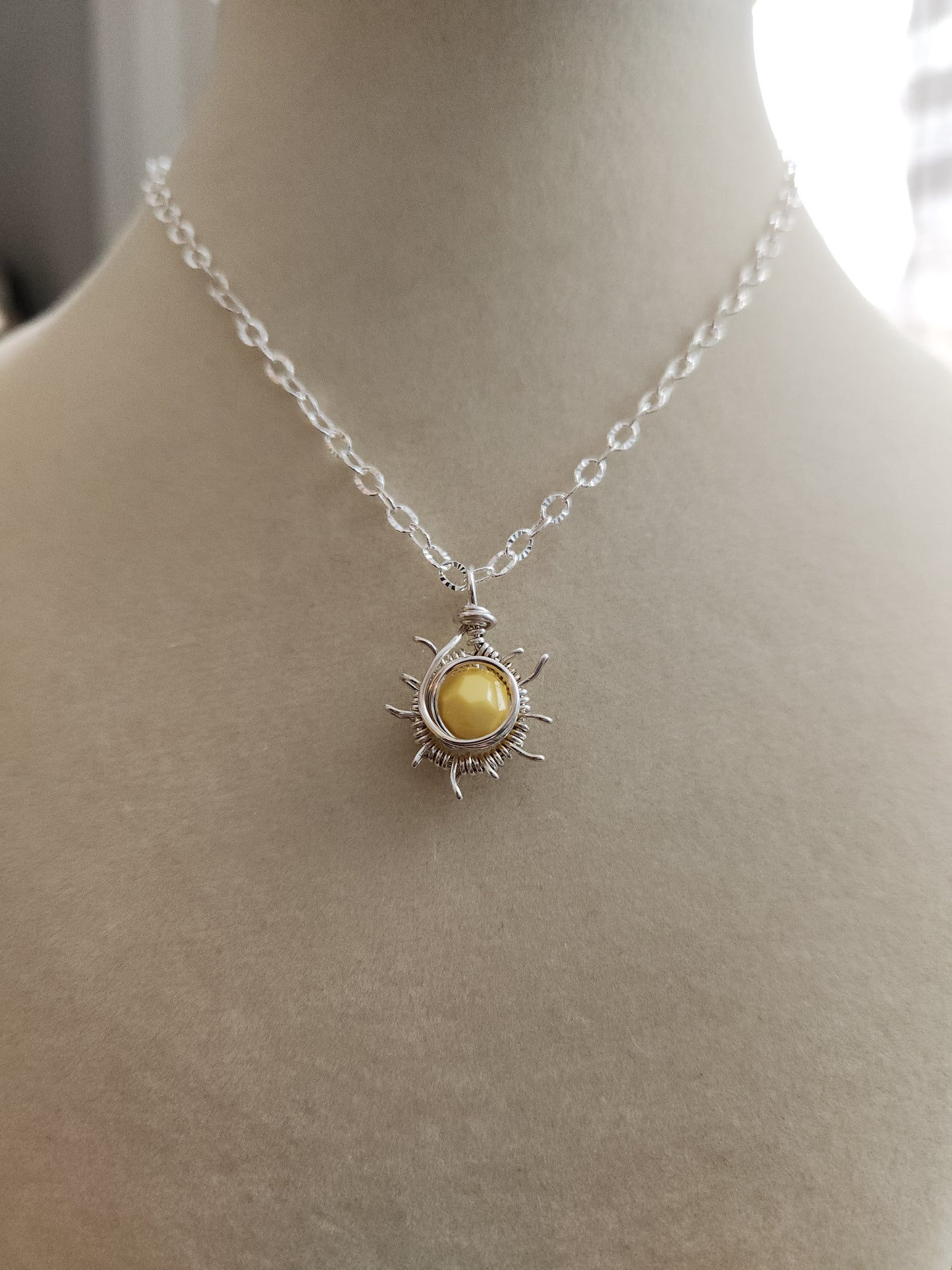 Sterling silver sun necklace featuring a golden gemstone pendant worn on the neck