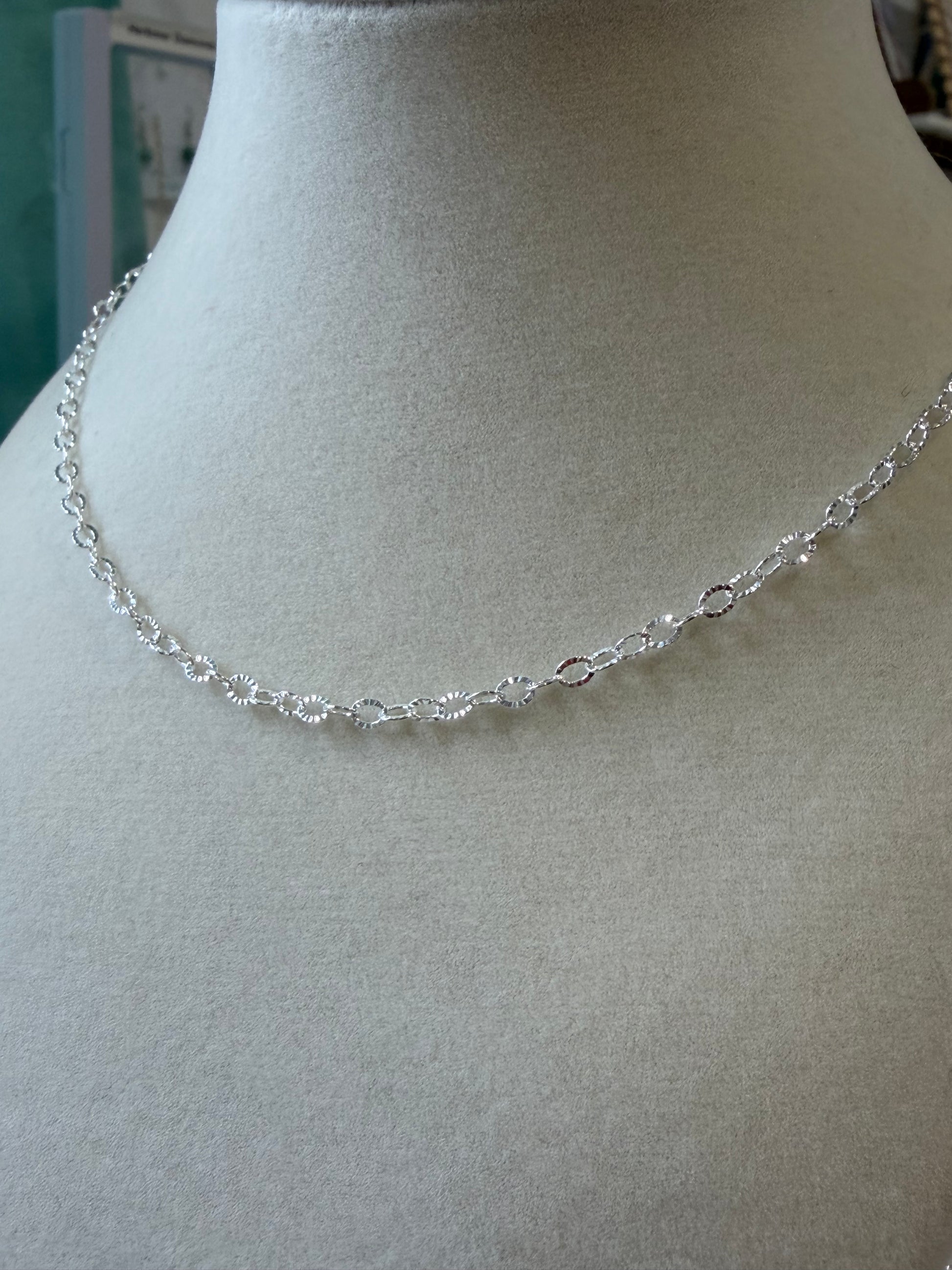 Close-up view of sterling silver sunburst chain links with textured finish